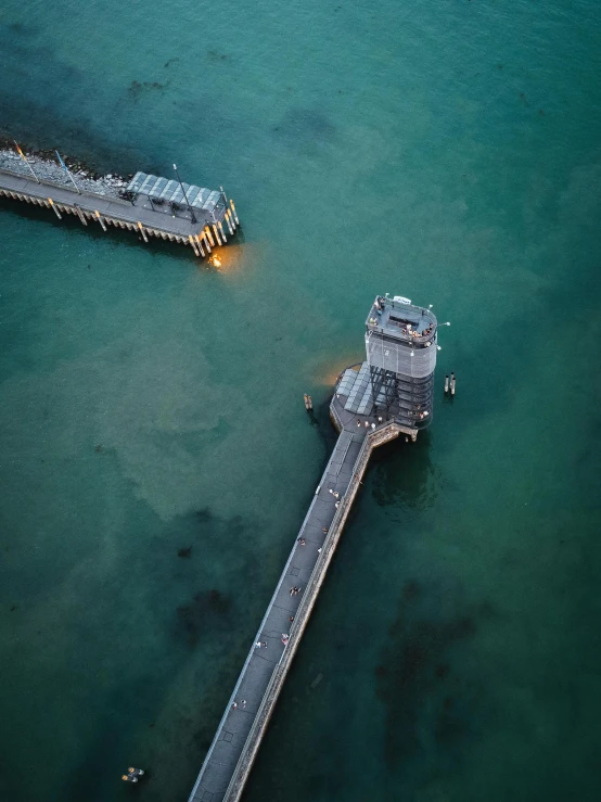 a small pier in the middle of water with two piers in the background