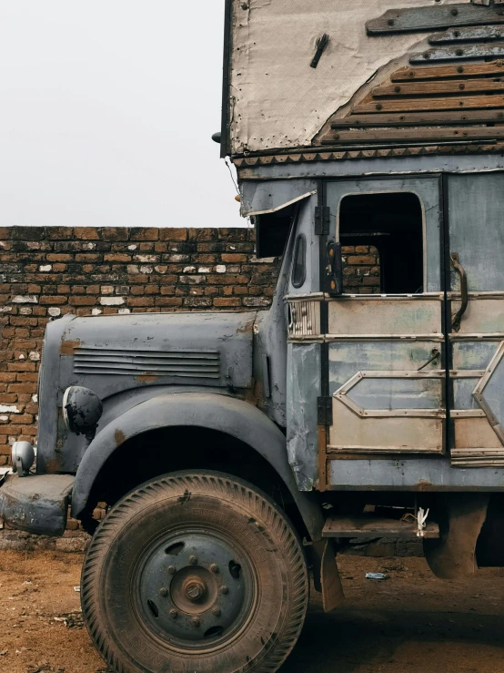 an old dirty truck is parked next to a building