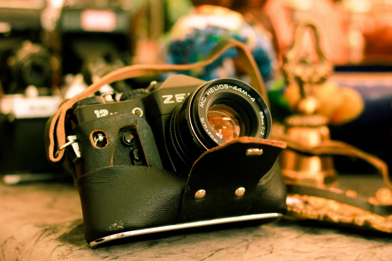 a vintage black camera with leather case sitting on a table