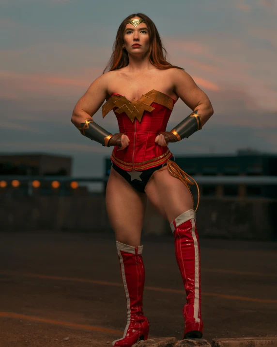 a beautiful woman in red boots and a costume standing in front of a sunset