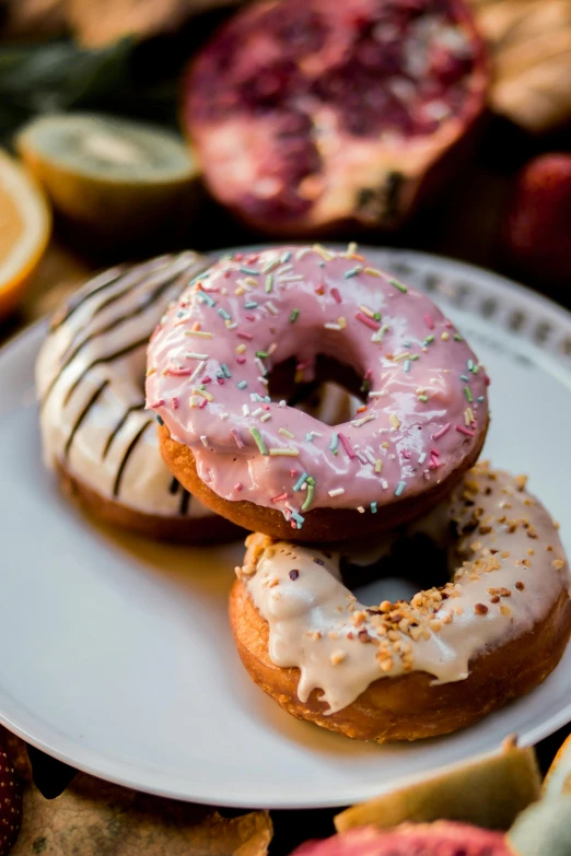three doughnuts are on a plate with pink icing