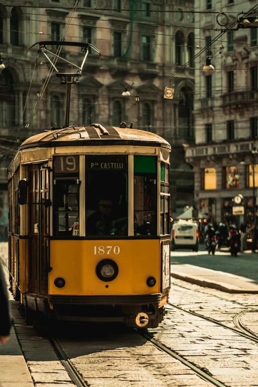 an old style trolley car on a road near buildings