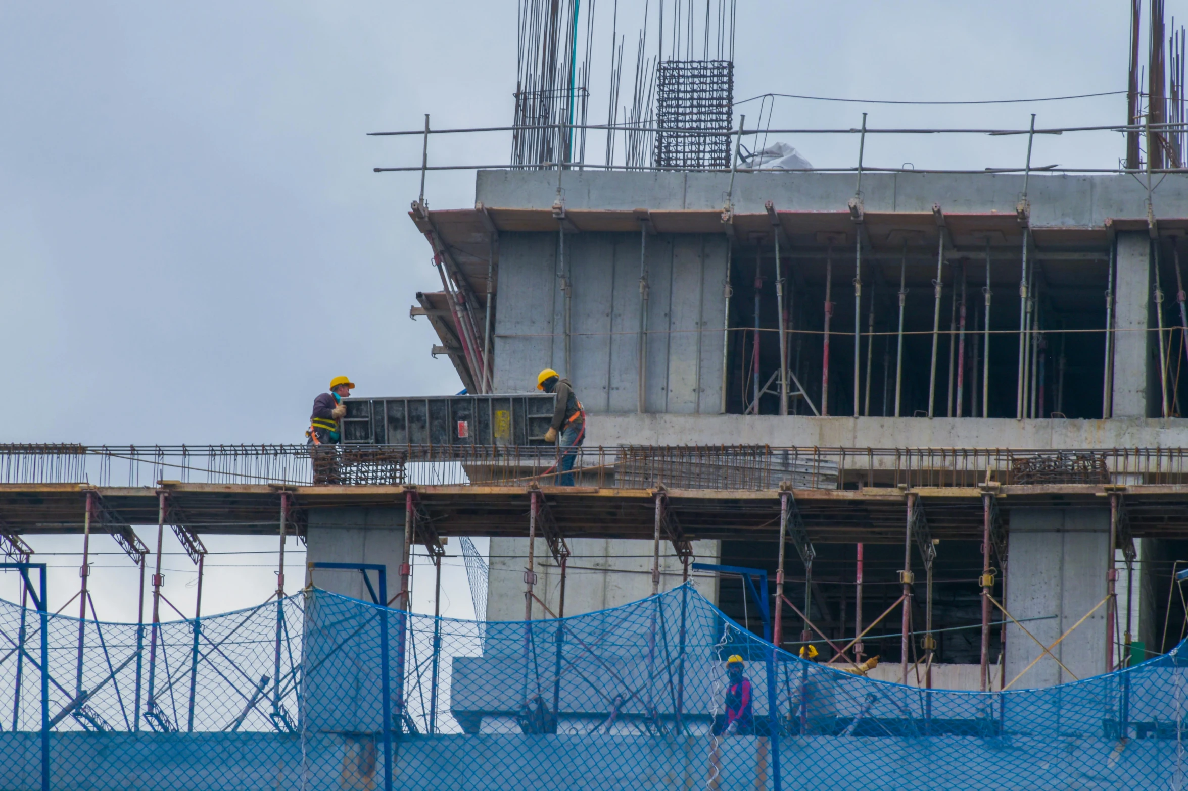 two construction workers stand on top of the building