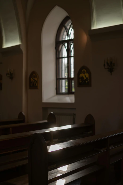 sunlight shines through an arched window into the pews of a church