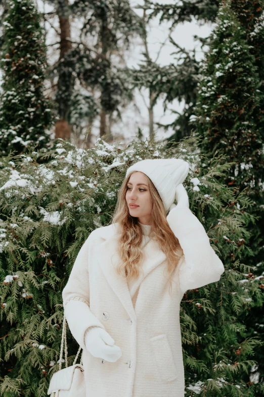 a beautiful woman standing in the snow wearing white