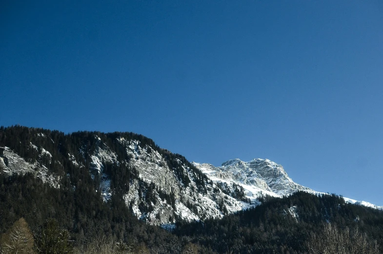 snow covered mountains with green trees on the sides