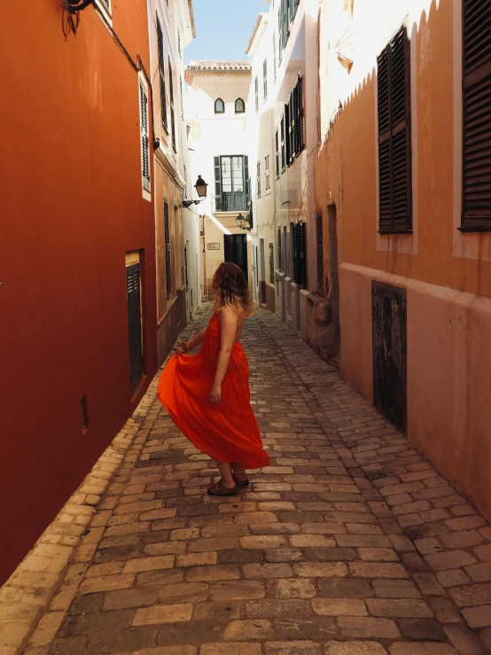 a woman in an orange dress stands on the brick path