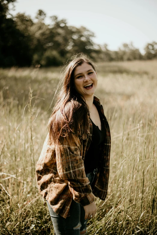 an attractive young woman standing in tall grass