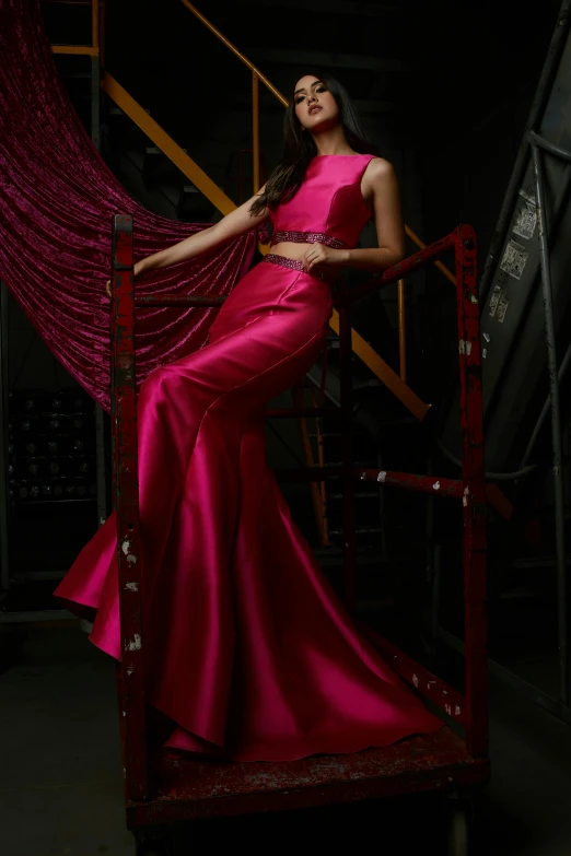 a woman in a pink gown is standing on a stair case