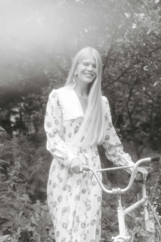 a beautiful woman standing beside a bike wearing a robe