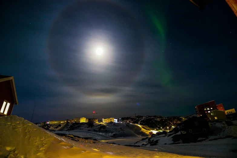 a bright circle in the night sky above a mountain