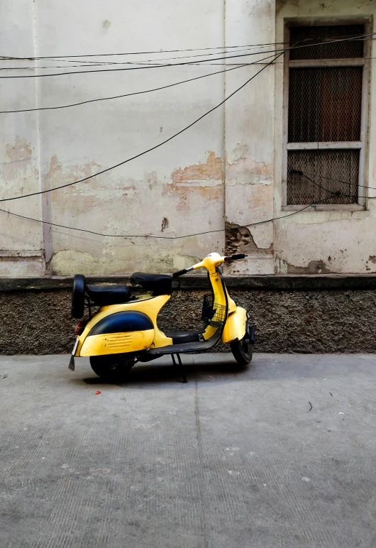 a scooter is parked on the pavement in front of a building