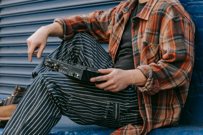 a man sitting against a wall with his cell phone