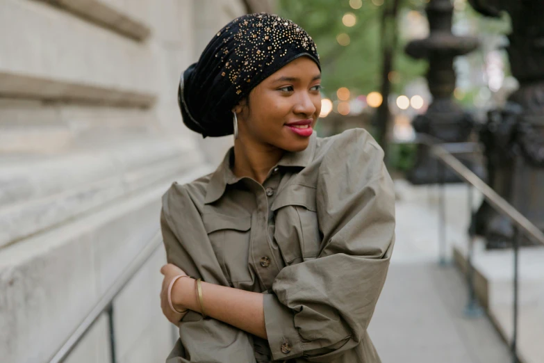 an african american woman standing on a sidewalk with her arms crossed