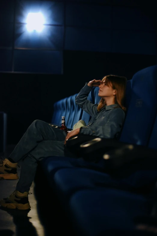 woman sitting on blue seats drinking a soda