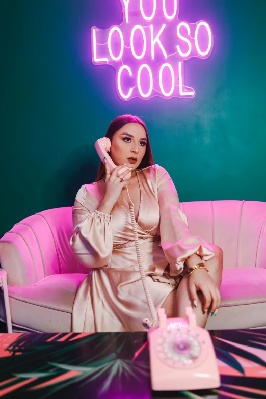 a woman with a phone sitting on top of a pink couch
