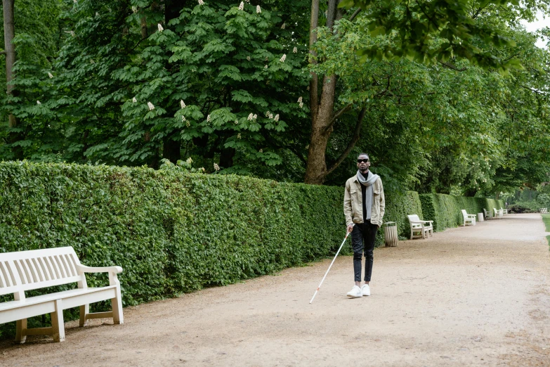 a person is walking down a path with a walking stick