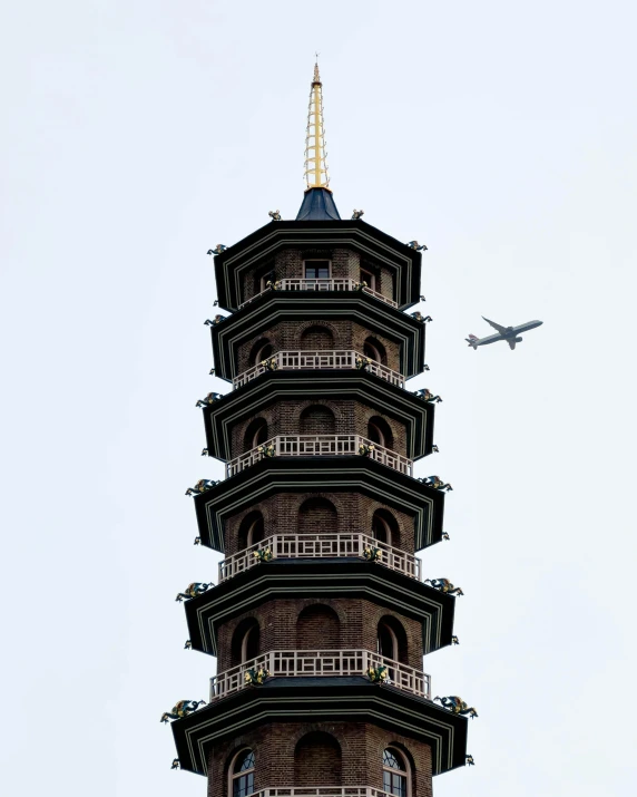 an airplane flies by the tall pagoda building