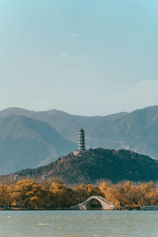 a tower sits on a hill overlooking a body of water