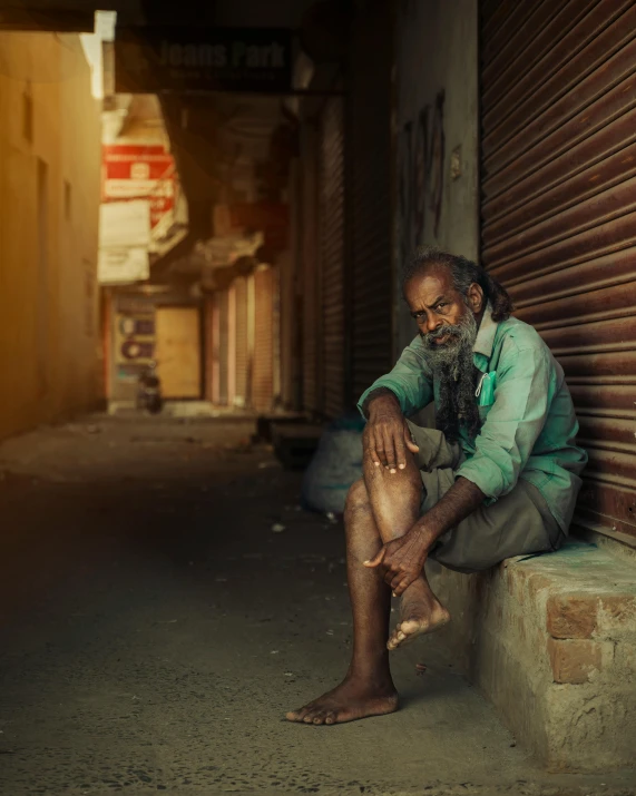 an old man sitting on a ledge by a building