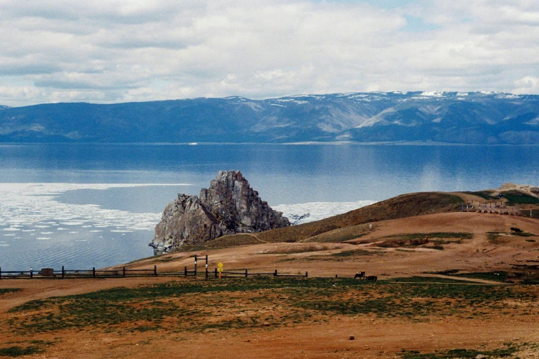 some people are in the grass a large mountain and water