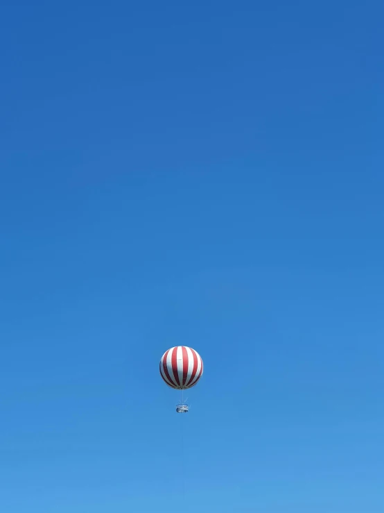 an air ballon in the sky, with a parachute