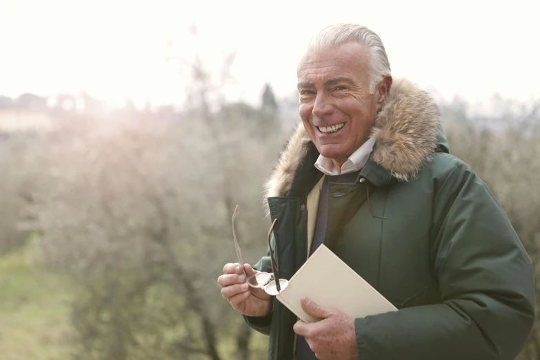 a man with an open folder laughing on a field