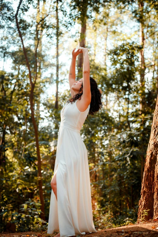 the young woman is dressed in all white posing for a po in the woods