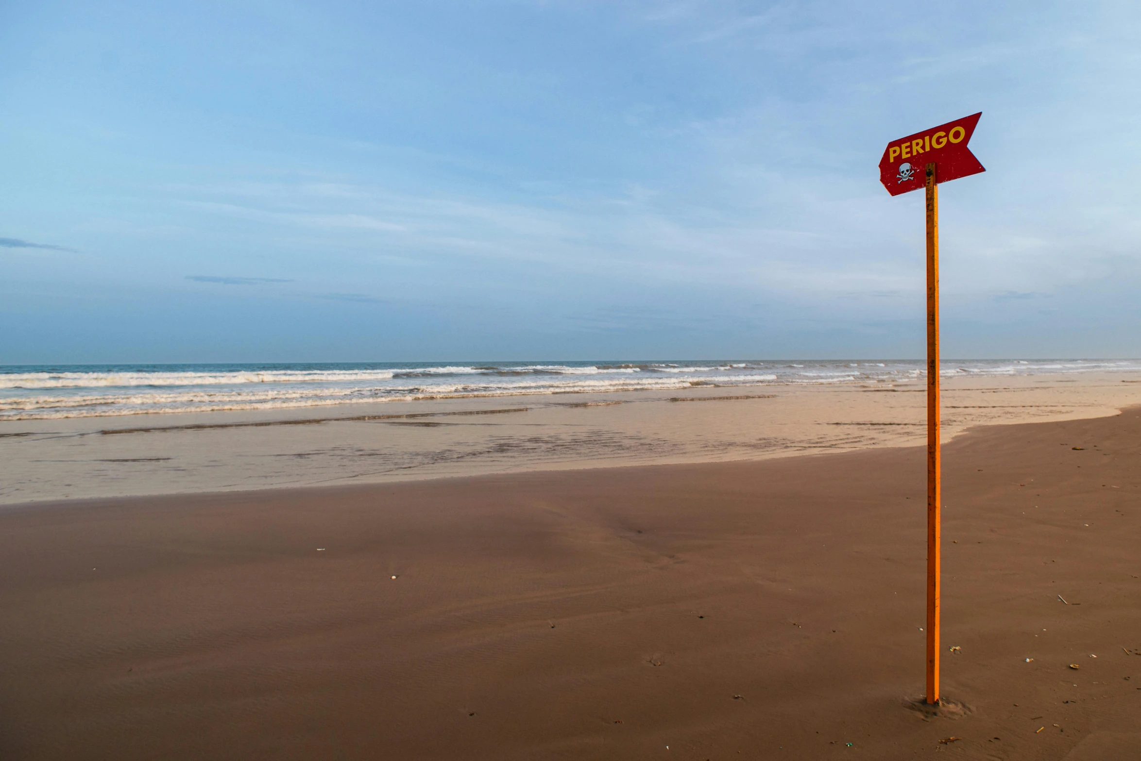 a red street sign sitting on top of a sandy beach