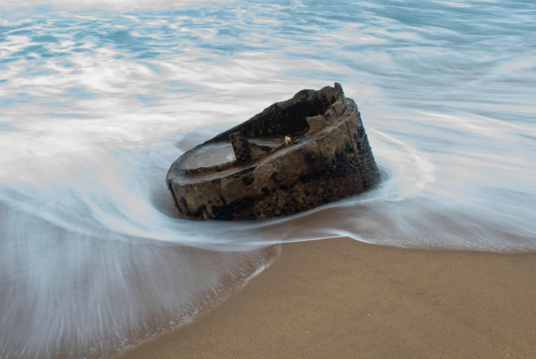 a dirty broken boat on the sand near the water