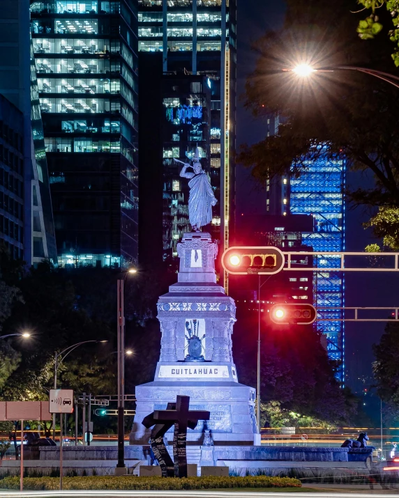 a statue stands in front of a lit up street