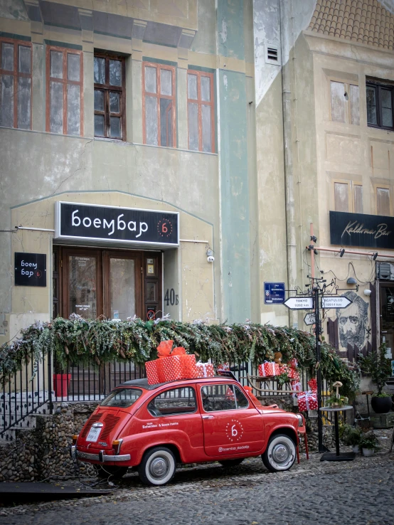 there is a small red car parked in front of a tall building