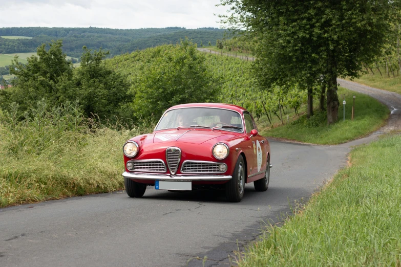 an old red car is on a paved road