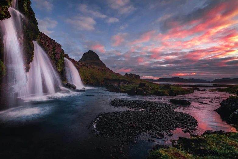 a beautiful waterfall and some rocks at sunset