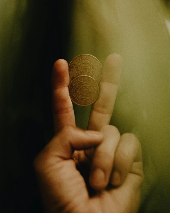 a man holding up a small piece of silver dollar