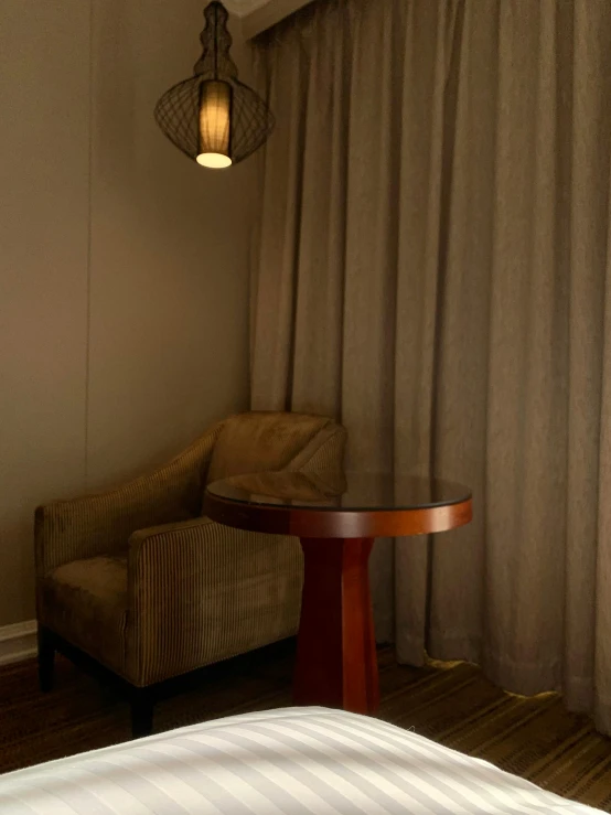 a chair next to a table and a light on a wall