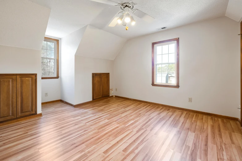 an empty living room with wooden flooring and a ceiling fan