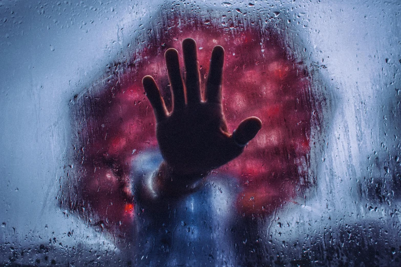 a person is holding their hand out through a wet window