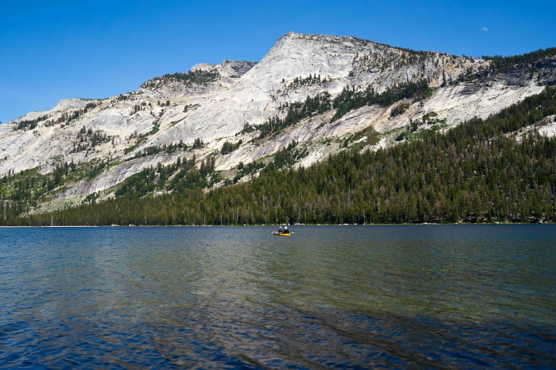 boats are anchored along the shore near some mountains