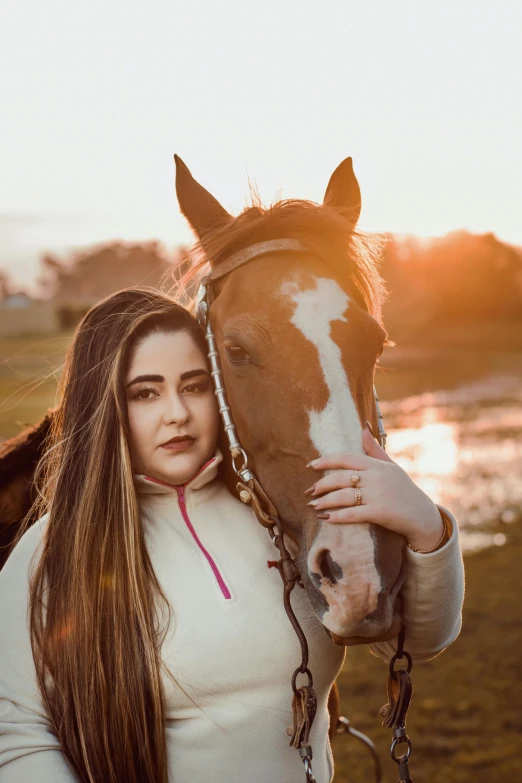 a woman standing next to a brown horse near a body of water