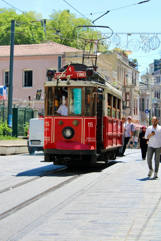 a train coming down the road with people walking on the side