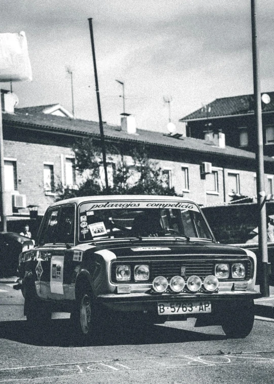 a vintage car driving down the street as people look on