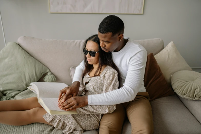 two people sitting together on a couch and holding their hands