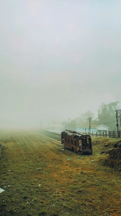 a train sitting in the middle of a field in the fog