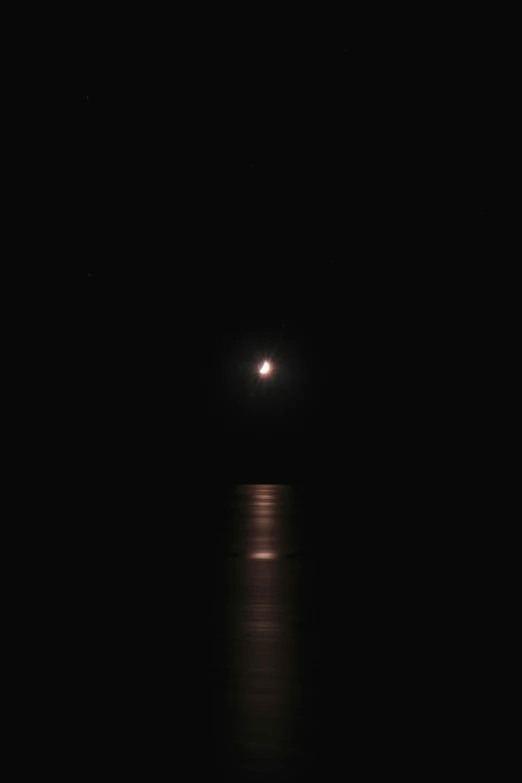 the moon is shining in the dark sky above the water