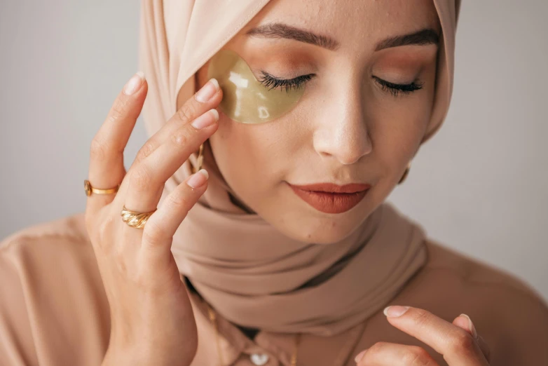 a beautiful young woman putting cosmetics on her face