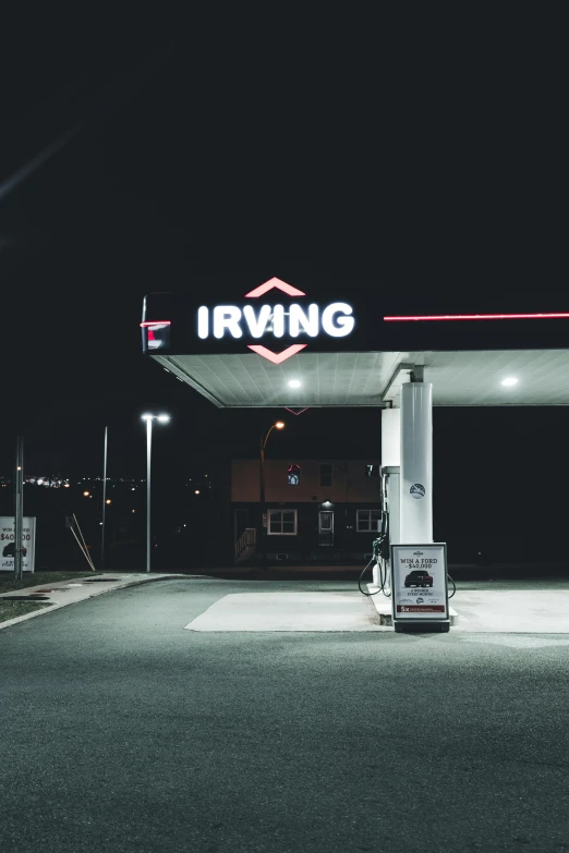 an old - fashioned gas station is lit up at night