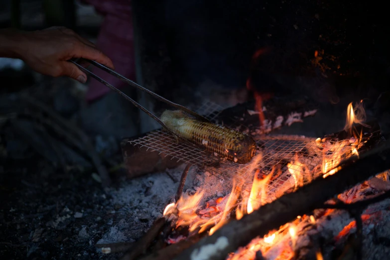 a person is using tongs to roast food over fire