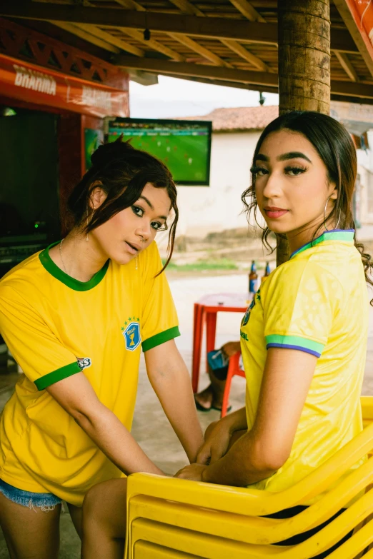 two young women pose together wearing bright yellow shirts