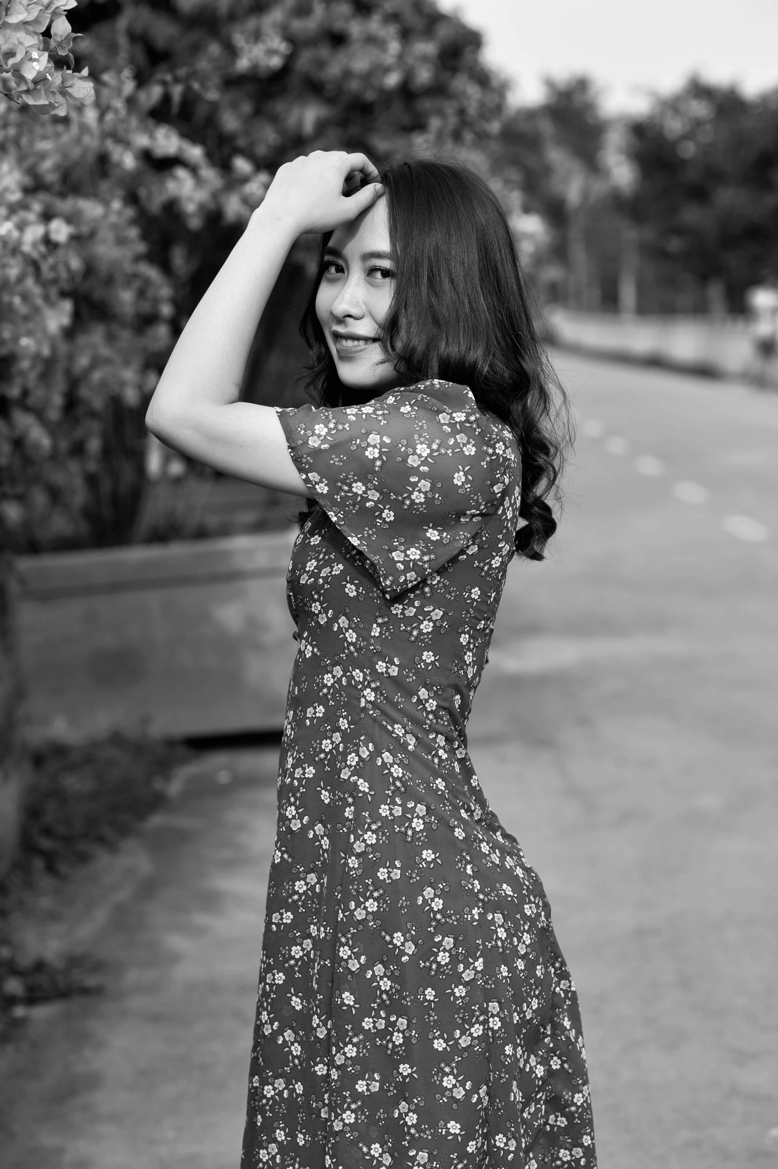 woman in a floral dress standing near a fence